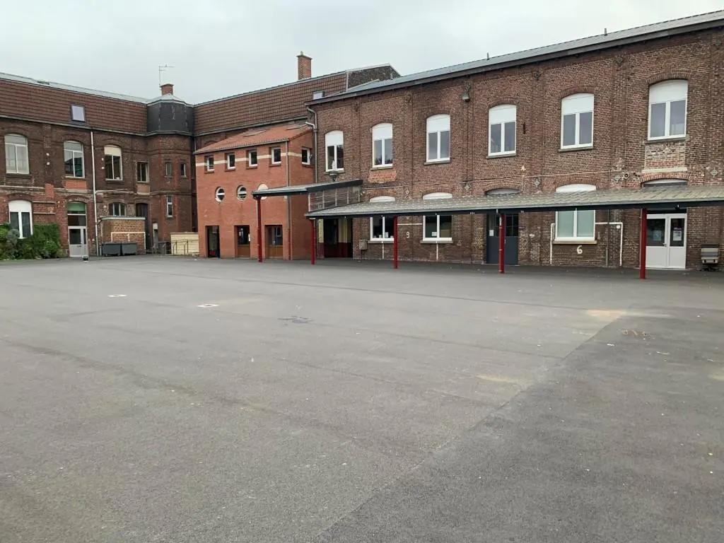 La cour du collège, entourée de ses bâtiments en briques.