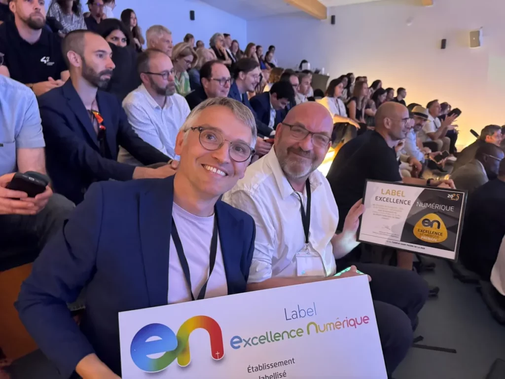 Deux membres de l’équipe du collège présentent le panneau « Label Excellence Numérique, établissement labellisé » lors de la remise du label.